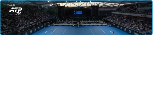 Un stade de tennis avec vue sur le court rempli de spectateurs pendant la nuit. Les joueurs sont en plein match.