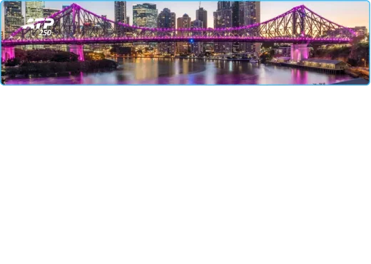 Pont illuminé de lumières violettes au-dessus d'une rivière réfléchissante, avec en toile de fond les gratte-ciel de la ville au crépuscule, créant une scène urbaine vibrante.