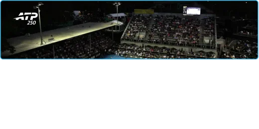 Événement sportif nocturne en plein air avec des tribunes remplies et des projecteurs éclairant la scène. Une atmosphère énergique est capturée alors que les spectateurs regardent attentivement.
